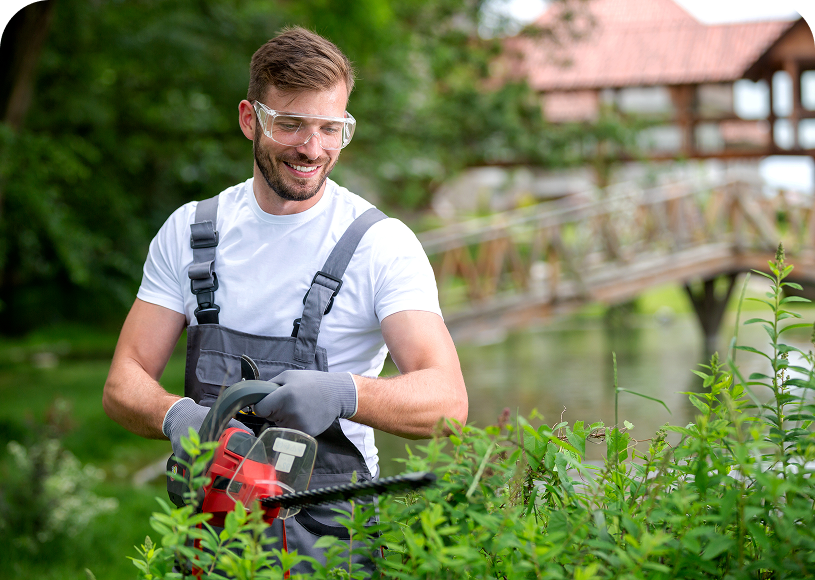Man trimming bushes with chainsaw outdoors